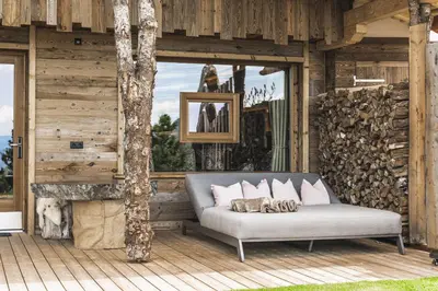 a couch sitting on a wooden deck with a window at Kirchwies Naturchalet - Adults Only in Laion