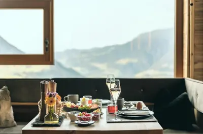 a table with a plate of food and a glass of wine at Kirchwies Naturchalet - Adults Only in Laion