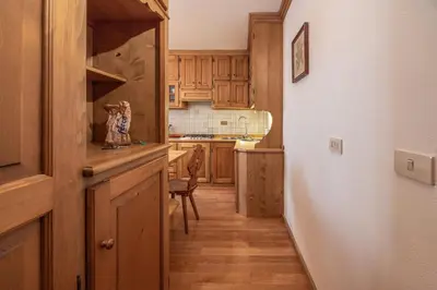 a small kitchen with wooden cabinets and a table at Casa Ronco, tranquilla e confortevole in Cortina dʼAmpezzo