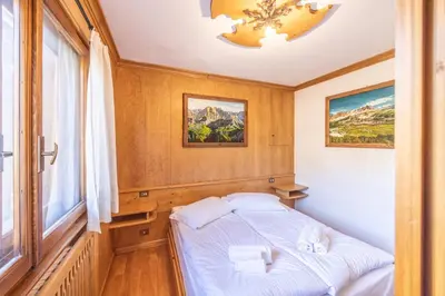 a small bed in a room with a window at Casa Ronco, tranquilla e confortevole in Cortina dʼAmpezzo