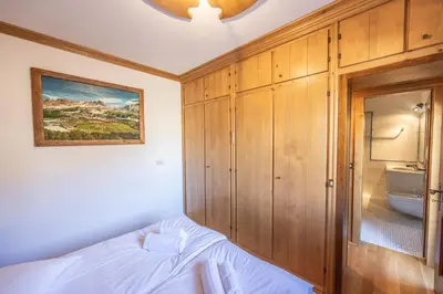 a bedroom with a bed and a bathroom at Casa Ronco, tranquilla e confortevole in Cortina dʼAmpezzo