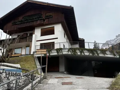 a house with a garage in front of it at Casa Ronco, tranquilla e confortevole in Cortina dʼAmpezzo