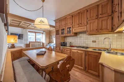 a kitchen with wooden cabinets and a wooden table at Casa Ronco, tranquilla e confortevole in Cortina dʼAmpezzo