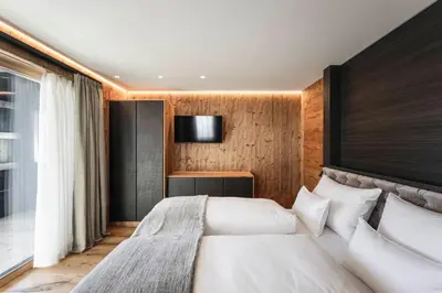 a bedroom with two beds and a tv on the wall at DISTINCTIVE LUXURY DOLOMITI Apartments TERRE71 in San Vigilio Di Marebbe