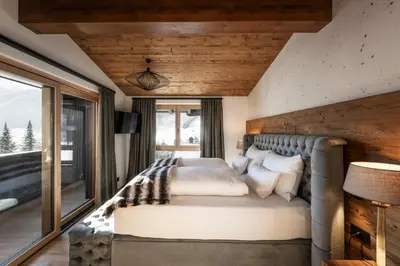 a bedroom with a bed with a large window at DISTINCTIVE LUXURY DOLOMITI Apartments TERRE71 in San Vigilio Di Marebbe