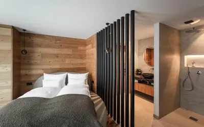a bedroom with a large bed and a bathroom at DISTINCTIVE LUXURY DOLOMITI Apartments TERRE71 in San Vigilio Di Marebbe