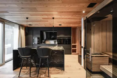 a kitchen with a black counter and stools at DISTINCTIVE LUXURY DOLOMITI Apartments TERRE71 in San Vigilio Di Marebbe