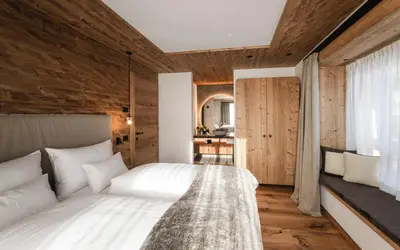 a bedroom with a white bed and wooden walls at DISTINCTIVE LUXURY DOLOMITI Apartments TERRE71 in San Vigilio Di Marebbe