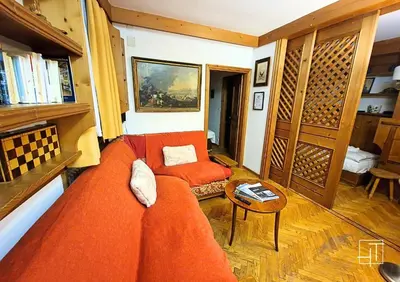 a living room with an orange couch and a table at HT - Ciasa Ca'Mora nel centro di Cortina d'Ampezzo in Cortina dʼAmpezzo