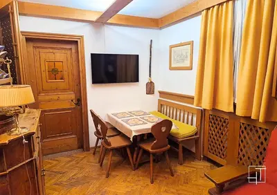 a dining room with a table and chairs and a television at HT - Ciasa Ca'Mora nel centro di Cortina d'Ampezzo in Cortina dʼAmpezzo