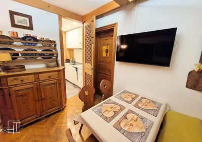 a dining room with a table and a kitchen at HT - Ciasa Ca'Mora nel centro di Cortina d'Ampezzo in Cortina dʼAmpezzo