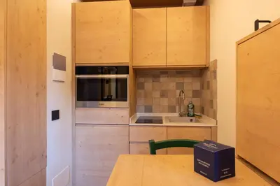a small kitchen with wooden cabinets and a table at Casa Zardini, in centro a Cortina d'Ampezzo in Cortina dʼAmpezzo