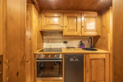 a kitchen with wooden cabinets and a sink and a stove at Chiara Home, in centro a Cortina d Ampezzo in Cortina dʼAmpezzo