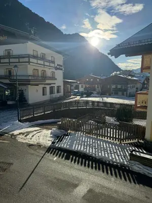 a fence in front of a building with the sun shining at Cèsa Emily in Campitello di Fassa