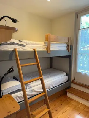 two bunk beds in a room with a ladder at Cèsa Emily in Campitello di Fassa