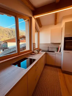 a kitchen with white cabinets and a large window at Apartment Ploseblick in Bressanone