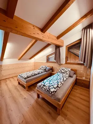 two beds in a room with wooden ceilings at Apartment Ploseblick in Bressanone