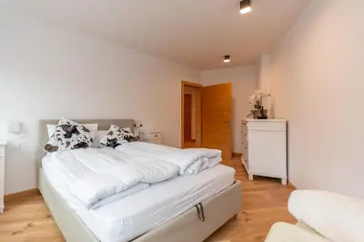 a bedroom with a large bed with white sheets at Ciesa dela Maestra in Rocca Pietore