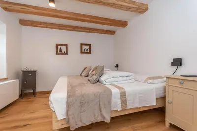 a bedroom with a bed with white sheets and wooden floors at Ciesa dela Maestra in Rocca Pietore