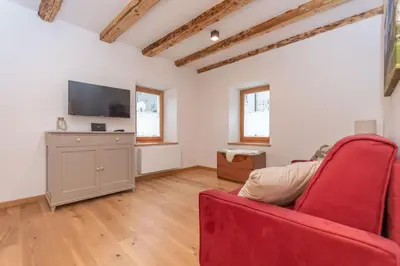 a living room with a red couch and a flat screen tv at Ciesa dela Maestra in Rocca Pietore