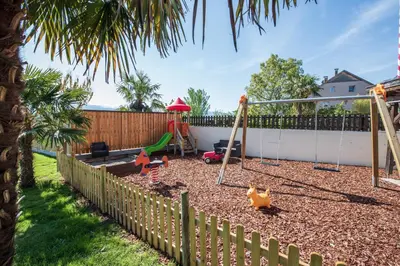 a playground with swings and toys in a backyard at Garni Gartenheim in Caldaro