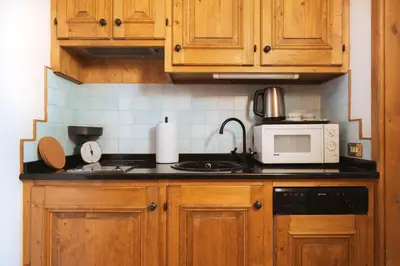 a kitchen with wooden cabinets and a microwave at GuestHost - Cortina Heart Retreat with Parking in Cortina dʼAmpezzo