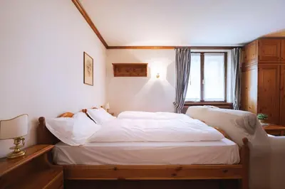 a bedroom with two beds with white sheets and a window at GuestHost - Cortina Heart Retreat with Parking in Cortina dʼAmpezzo
