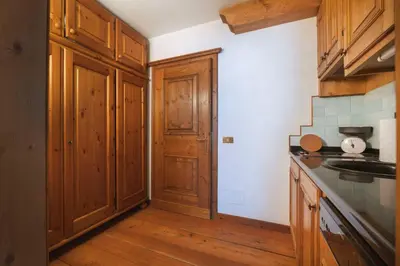 a kitchen with wooden cabinets and a wooden floor at GuestHost - Cortina Heart Retreat with Parking in Cortina dʼAmpezzo