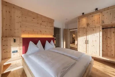 a bedroom with a large bed with wooden walls at A-Lunis in Brunico