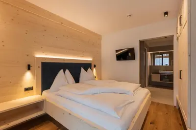 a large white bed in a room with wooden walls at A-Lunis in Brunico