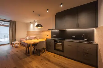 a kitchen with black cabinets and a wooden table at A-Lunis in Brunico