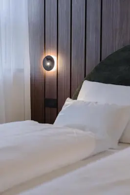 a bedroom with a white bed with a wooden wall at NAOMI Rooms in Salorno sulla Strada del Vino