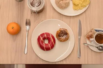 a table with two plates of breakfast foods and an orange at NAOMI Rooms in Salorno sulla Strada del Vino