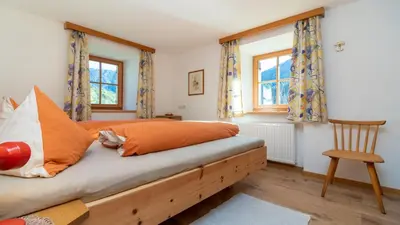 a bedroom with a bed with orange pillows and a chair at Spinuserhof in Tires