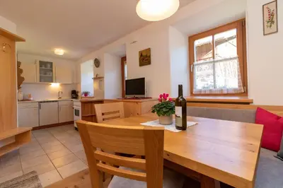 a kitchen and dining room with a table and a bottle of wine at Spinuserhof in Tires