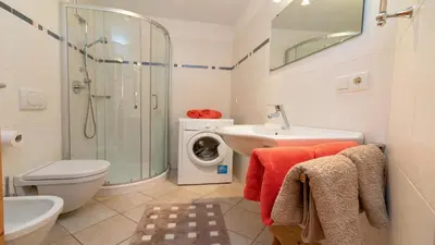 a bathroom with a sink toilet and a washing machine at Spinuserhof in Tires