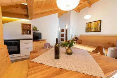 a kitchen and dining room with a table with a bottle of wine at Spinuserhof in Tires