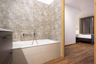 a bathroom with a bath tub and a bedroom at Apartments No7 Sella in Ortisei