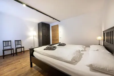 two beds in a bedroom with white walls and wooden floors at Apartments No7 Saslong in Ortisei