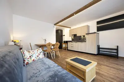 a living room with a couch and a table and a kitchen at Apartments No7 Saslong in Ortisei