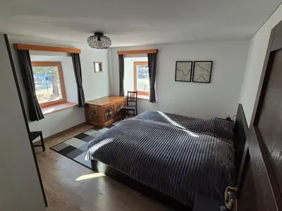 a bedroom with a bed and a table and windows at Casa Sasso Bianco in Rocca Pietore