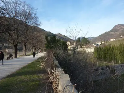 a person walking a dog on a sidewalk next to a hill at Apartment Leonardo in Bolzano