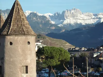 a clock tower with a mountain in the background at Apartment Leonardo in Bolzano