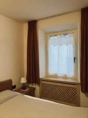 a bedroom with a bed and a window with curtains at CERMIS Minisuite in Cavalese