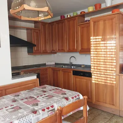 a kitchen with wooden cabinets and a table and a sink at casa elvira in Castello di Fiemme