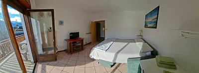 a small bedroom with a bed and a balcony at casa elvira in Castello di Fiemme