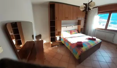 a bedroom with a bed and a large window at casa elvira in Castello di Fiemme