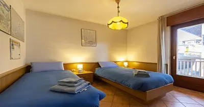 two beds sitting in a room with a window at casa elvira in Castello di Fiemme