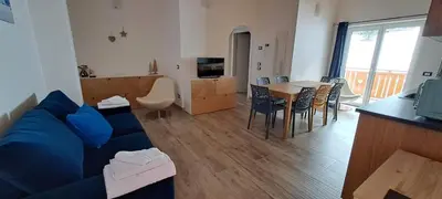 a living room with a blue couch and a table at Dream Apartments Moena in Moena