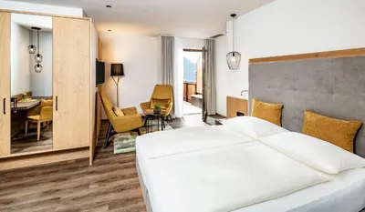 a bedroom with a white bed and a dining room at Hotel Krause in Tirolo